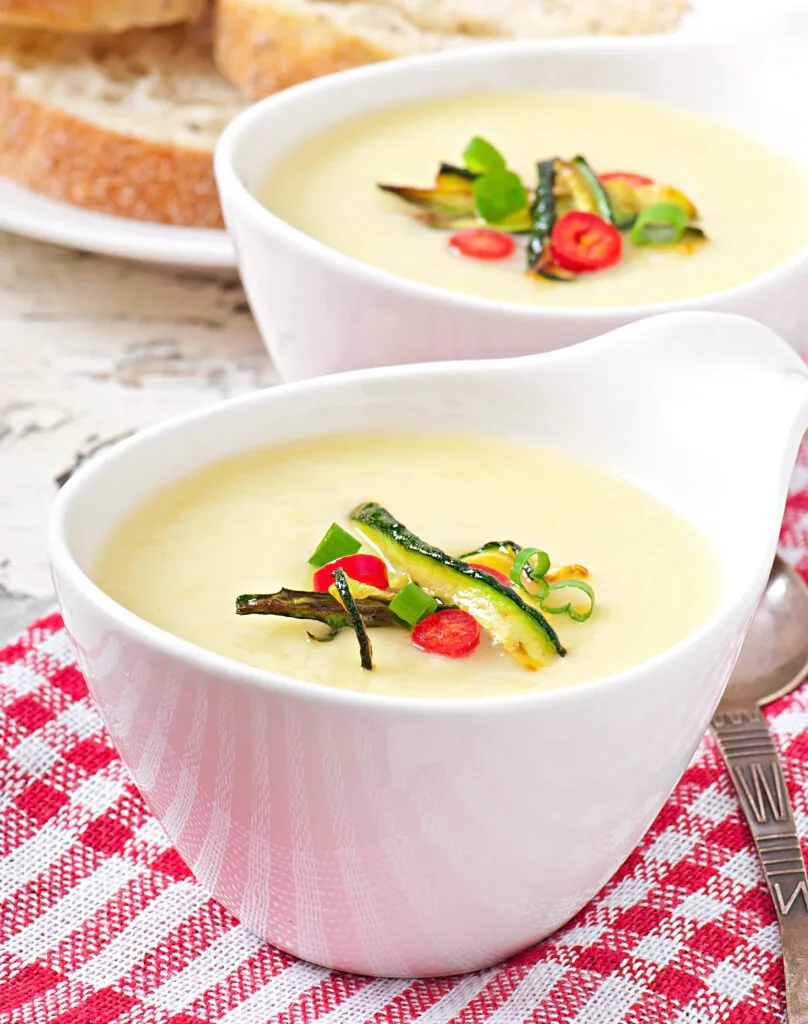 A bowl of creamy vegan potato leek soup topped with fresh herb oil.